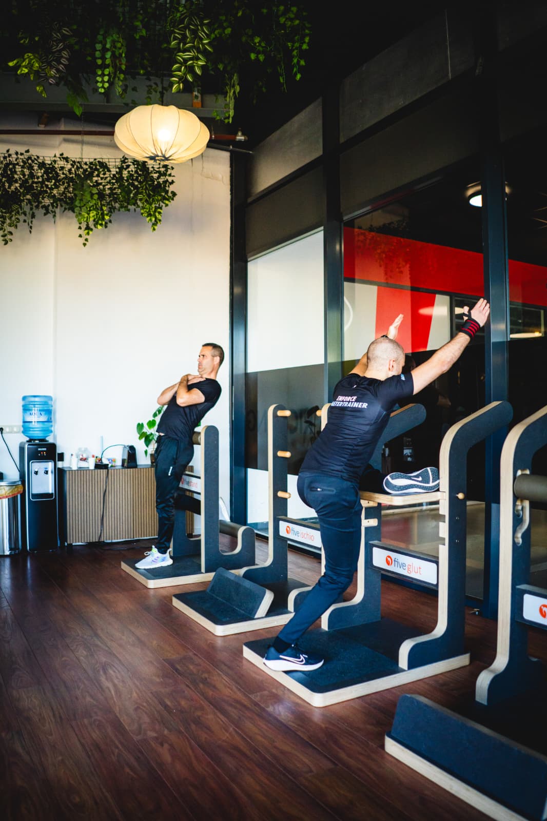 Coach begeleidt een lid tijdens krachttraining in een kleinschalige fitnessclub