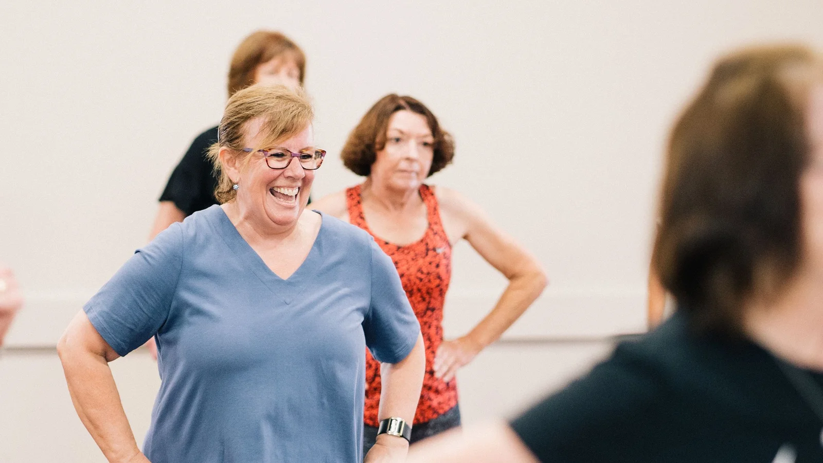 Een groep vrouwen van middelbare leeftijd volgt samen een actieve les in een zaal
